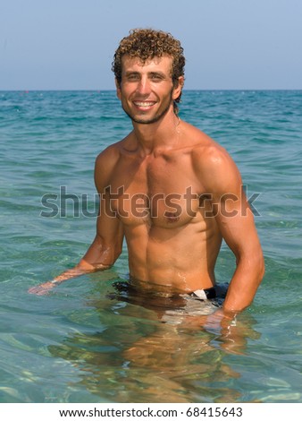 portrait of a young wet sexy muscular man standing in sea