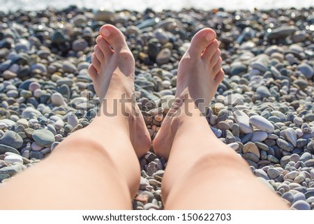 Feet girl sunbathing on sea stones
