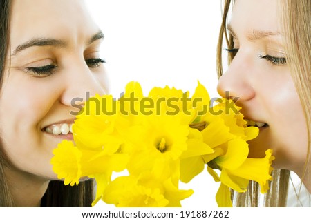 Two girls smell a bouquet a narcissus. The isolated background