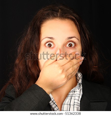 Scared young woman covering mouth on black background