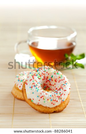 Cup of herbal tea with mint and couple of delicious tasty dough nuts on the beige table mat.