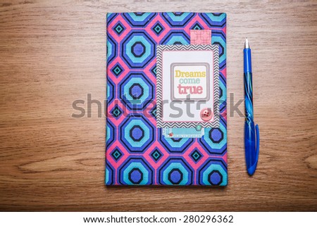 Color cover notepad with blue pen on the wooden table. View from above