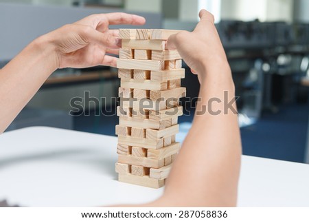 Man playing with the wood game (jenga) in the office