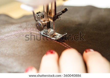 Women's hands behind her sewing. Sewing process with leather