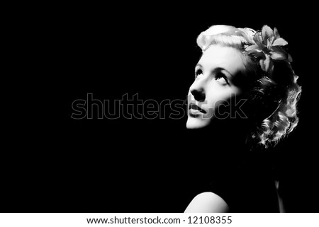 Forties hollywood black and white a beautiful woman stares right out of frame. Minimal lighting and strong contrast copy space to left