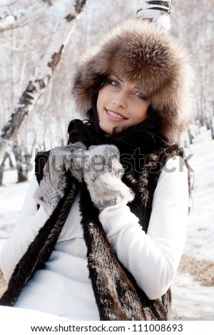 Young sexy woman in a fur hat and mittens in the early spring