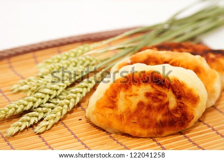 Fried pies with cabbage and wheat ears on a white napkin