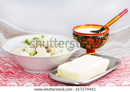 Dumplings with potatoes, sour cream in a wooden bowl and butter in a butter dish