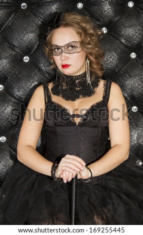 Girl in black dress with a black bow and painted black mask on eyes