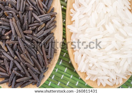 Two wooden spoons with black and white rice
