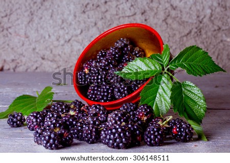 Ripe blackberries in a wooden bowl on the old wooden table