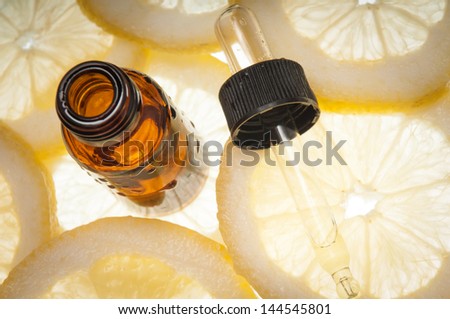 Essential oil amber glass bottle with dropper and some slices of lemon