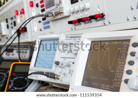 digital and analog oscilloscope in the foreground, in the background measuring devices with cables ready for measurements in electrical laboratory