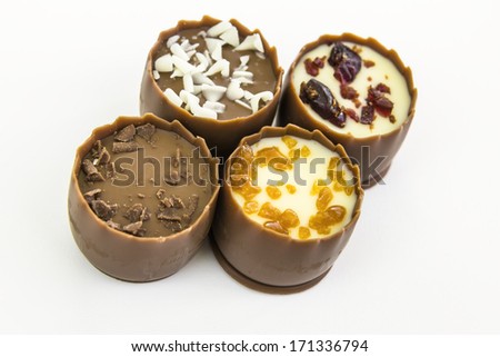 cream filled pralines of milk chocolate sprinkled with chocolate flakes, caramel and cranberry