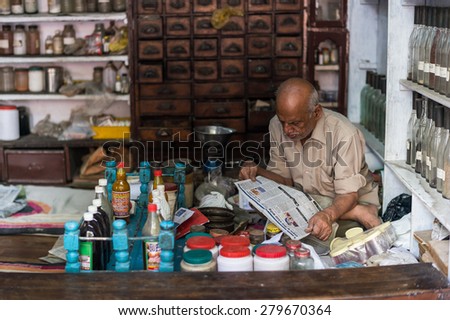 DELHI, INDIA-MAY 2014:  Unidentified people like shop keeper read news paper.