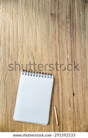 Blank note papers and pencil object on a wooden desk in Top view.
