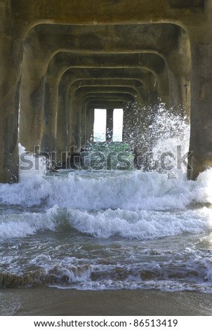 Waves crashing under a concrete pier in California