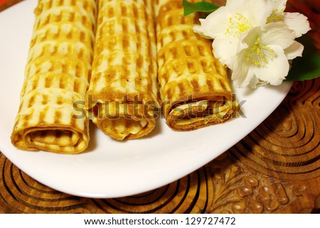 Wafer rolls on the table with flowers