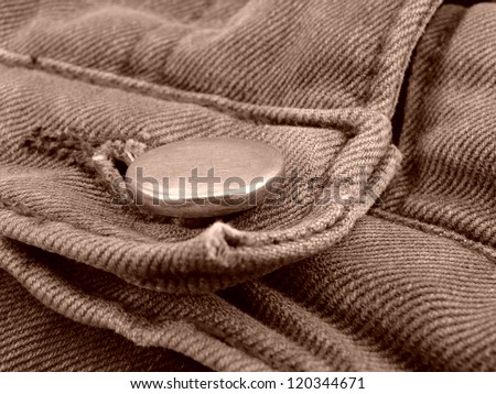 sepia toned worn-out denim fragment with a button