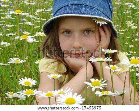 little girl portrait with wild daisies at the summertime meadow
