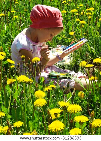 young painter paints among yellow dandelions at the sunny day