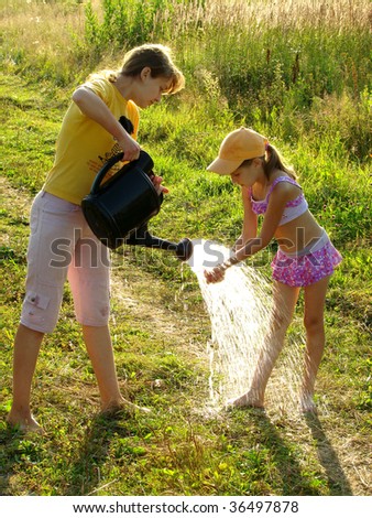 two sisters washing hands and legs from the watering can