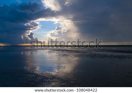 Cloudscape above the Dutch island of Ameland. In the front the tidal flats of the Wadden Sea.