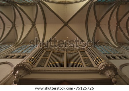Old organ under a cross vault. Silver and gold pipes at the crossing of a Dutch church.