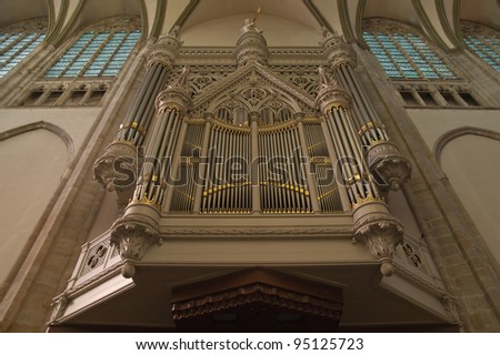 Big church organ with silver and golden pipes at the crossing of a Dutch church.