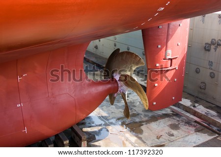Container vessel on dry dock. View over the rudder and propeller.