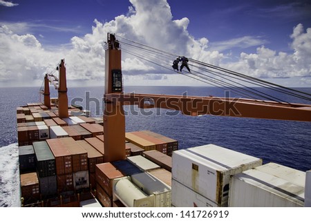 PACIFIC OCEAN - DECEMBER 4, 2008. Seamen grease steel wire of container ship\'s crane. Pacific Ocean on December 4.