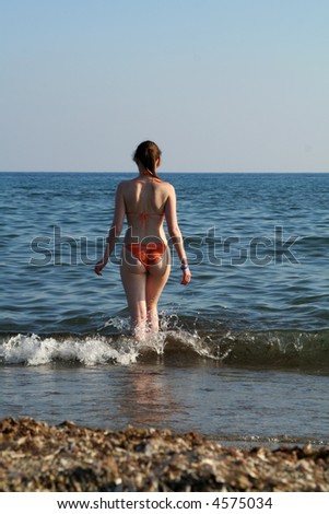 woman from behind view entering to sea