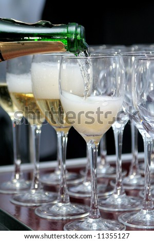 sparkling champagne bottle filling goblets with wine