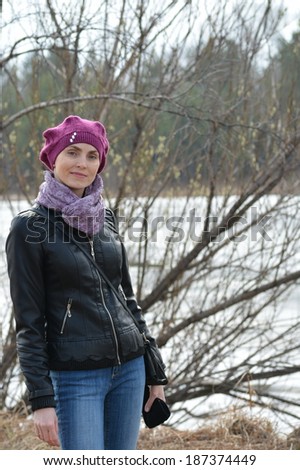 Woman in pink beret and black leather jacket against the background of water and forests