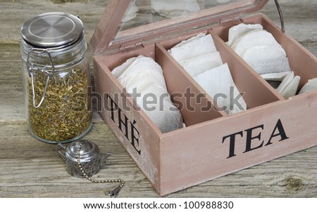 Loose tea in a spring top container and tea bags in a lettered box.