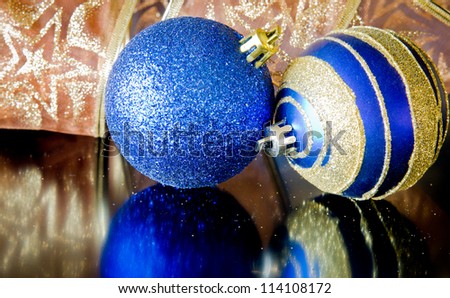 Blue Christmas ornaments with ribbon reflecting on a black surface