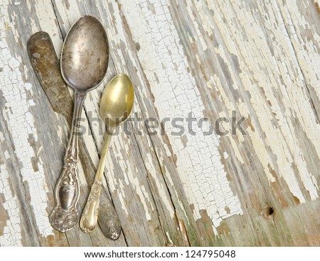 Antique silver spoons and a butter knife on a weathered plank surface