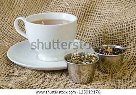 White tea cup with loose tea on a burlap surface