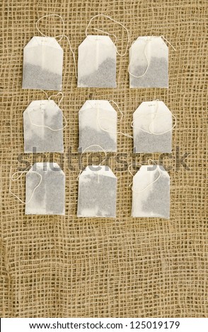 Nine tea bags on a burlap cloth.