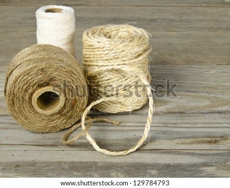 Three rolls of string on a wooden board surface