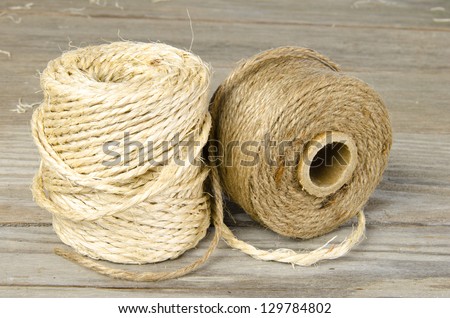 Two rolls of twine on a wooden board surface