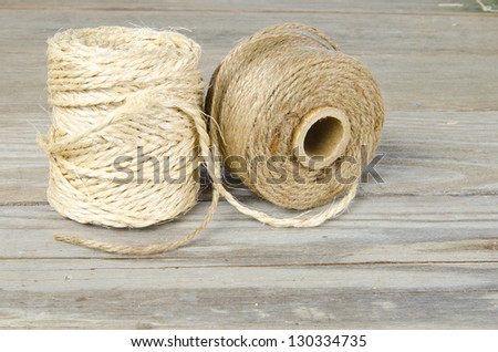 Two rolls of twine on a weathered board surface