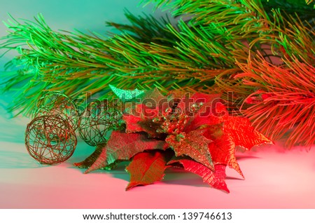 Christmas arrangement with poinsettia, pine bough and wire balls with red and green accent lighting
