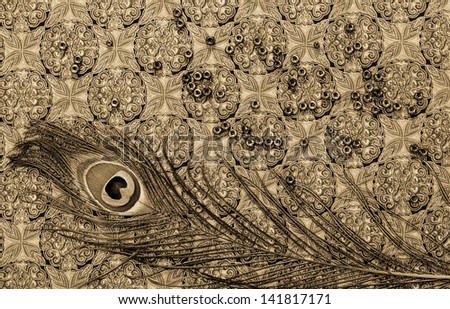 Toned image of peacock feather and beads on vintage printed fabric