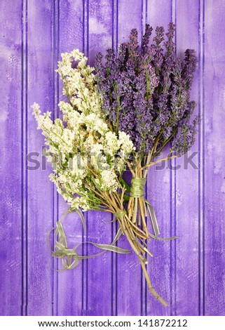 Dried bouquets of white and purple lilacs on a painted panel.
