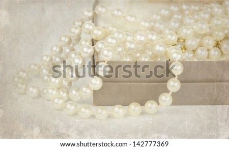 Vintage pearl beads spilling from a cotton filled cardboard box.