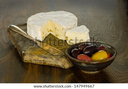 Brie cheese and a dish of olives with a rustic look