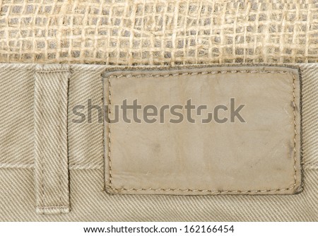 Close up of tan denim jeans with leather tag and burlap background.  Good background for Western themed business cards