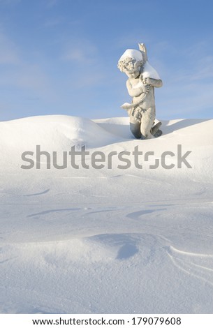 A statue of a cherub with a fish in a snow bank