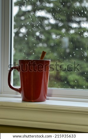 Mug of hot chocolate on a window sill with raindrops on window